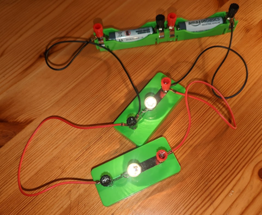 A circuit containing a two 1.5V batteries with an LED connected, and a second LED connected across it (the same way a Voltmeter would have been connected).