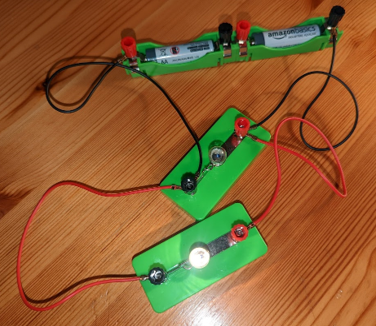 A circuit containing two AA batteries and two lightbulbs in parallel with each other. One of the lights is brightly lit.