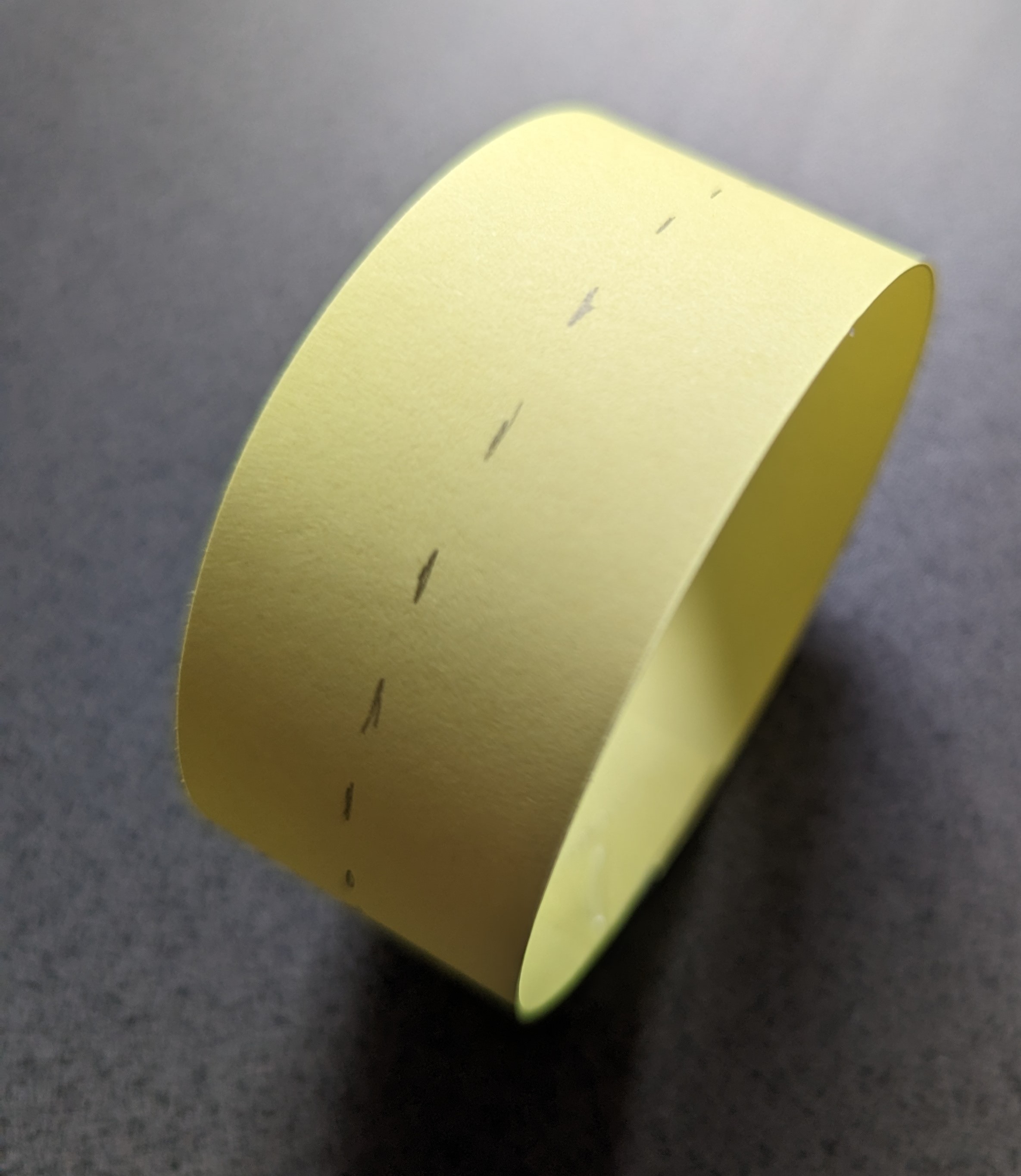 A strip of card connected into a loop with a dashed line drawn around the centre