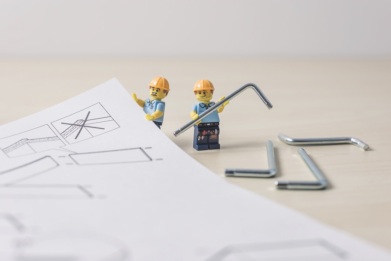 Two lego builders with allen keys and a set of assembly instructions