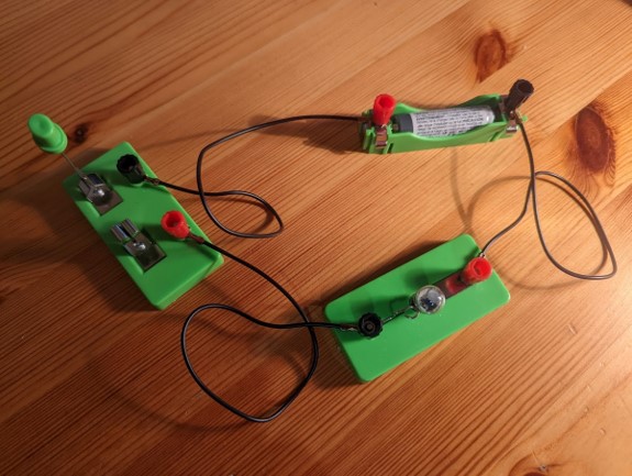 A circuit containing a battery, lightbulb, and a switch which is open (breaking the circuit)