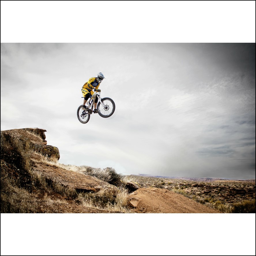 a mountain biker stunt jumping over a crag