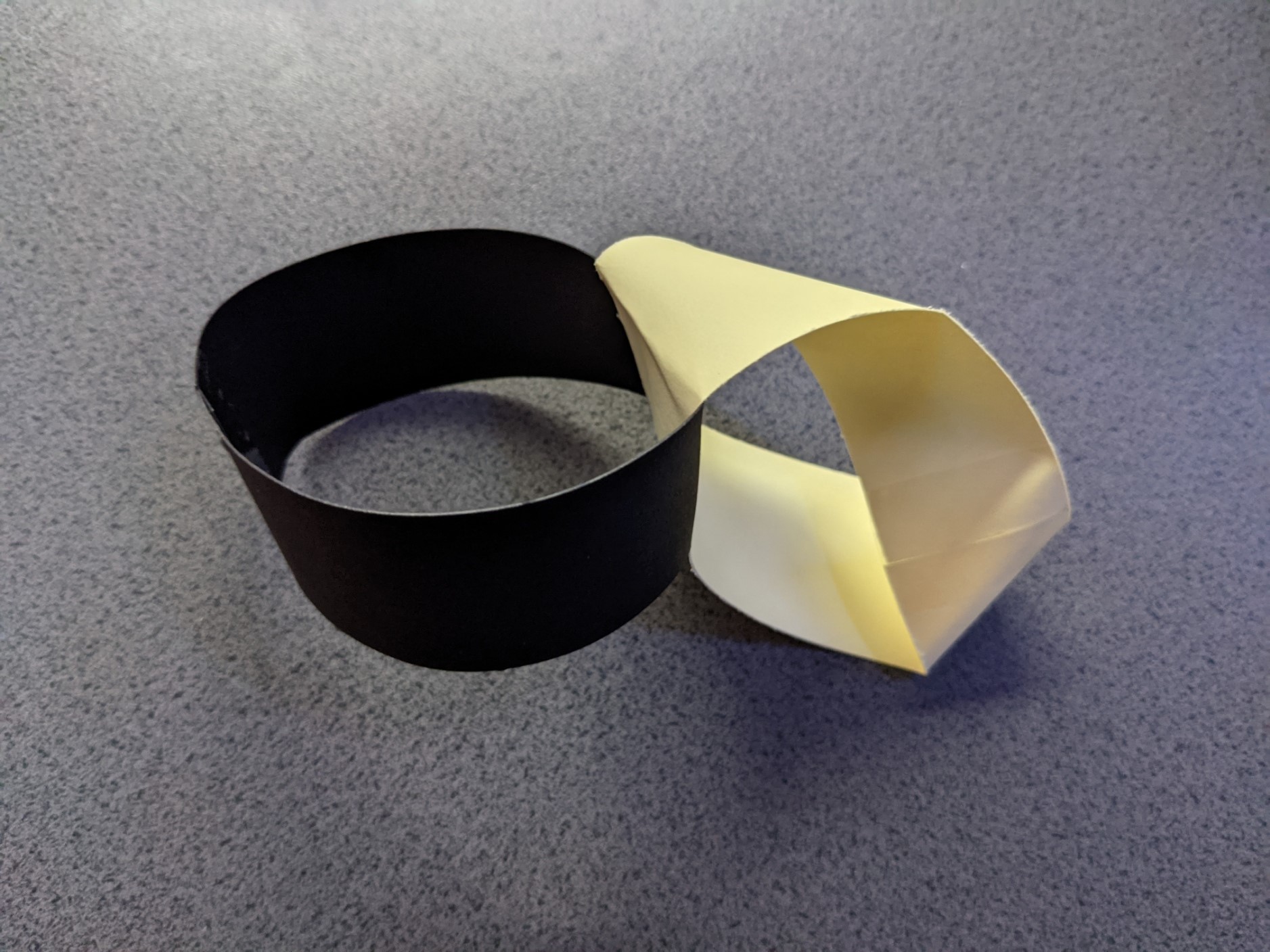 A simple loop of black card attached at right-angles to a Möbius Strip.